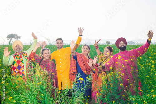 Punjabi sikh family doing bhangra dance in agriculture field celebrating Baisakhi or vaisakhi festival. photo