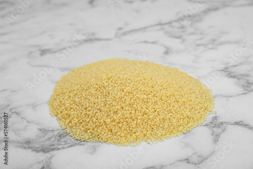 Heap of raw couscous on white marble table photo