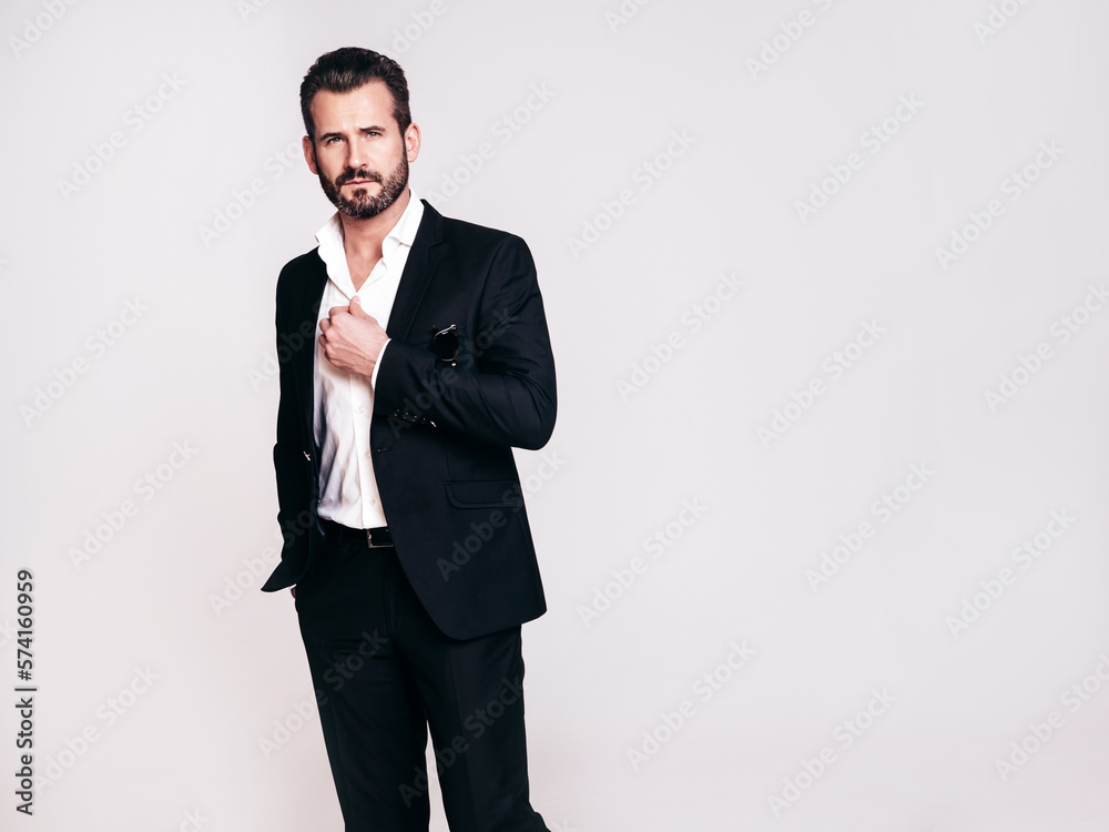 Portrait of handsome confident stylish hipster lambersexual model. Sexy modern man dressed in black elegant suit. Fashion male posing in studio, isolated on white Portrait of handsome confident stylish hipster lambersexual model. Sexy modern man dressed in black elegant suit. Fashion male posing in studio, isolated on white