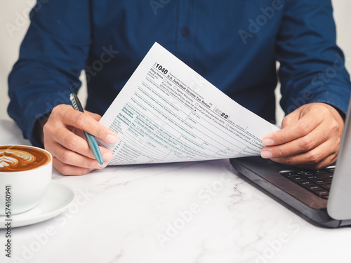 Hand holding of form 1040. U.S. individual income tax return while sitting at the table in the office photo