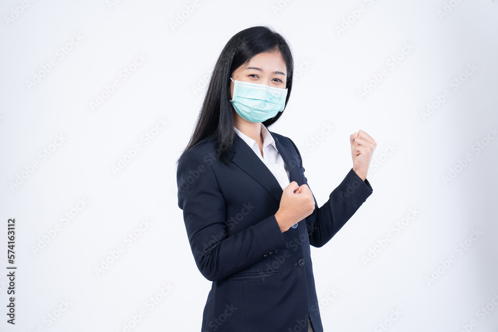 A confident beautiful young Asian business woman wearing green medical face mask and black suit, standing with her arms folded and looking at camera isolated on white background. A confident beautiful young Asian business woman wearing green medical face mask and black suit, standing with her arms folded and looking at camera isolated on white background.