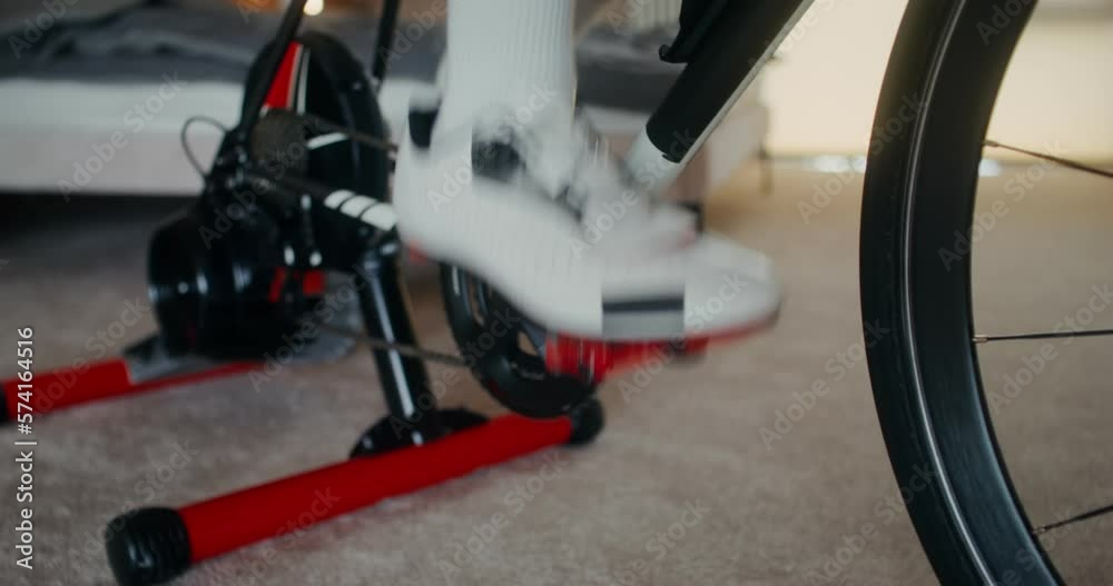 A man pedals a bicycle standing at a bicycle station, close-up of male legs, no face. Indoor cycling in a stylish home interior A man pedals a bicycle standing at a bicycle station, close-up of male legs, no face. Indoor cycling in a stylish home interior
