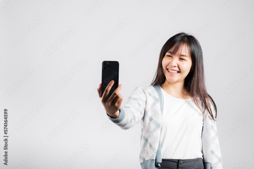 Woman excited holding smartphone to shooting selfie photo front camera studio shot isolated white background, happy young female smiling taking photography by mobile phone on mobile phone