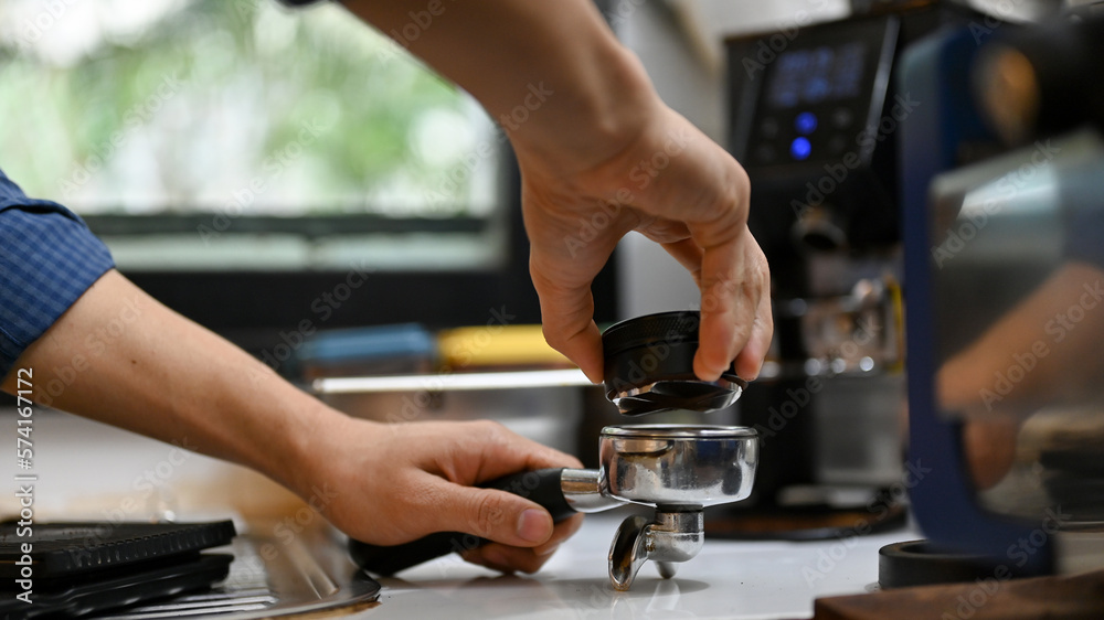 Male barista using Macaron tamper or coffee face spreader to spread the coffee face before tamper Male barista using Macaron tamper or coffee face spreader to spread the coffee face before tamper