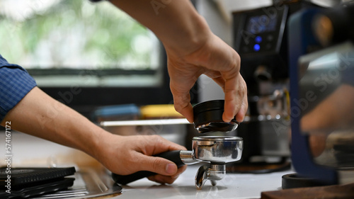 Male barista using Macaron tamper or coffee face spreader to spread the coffee face before tamper