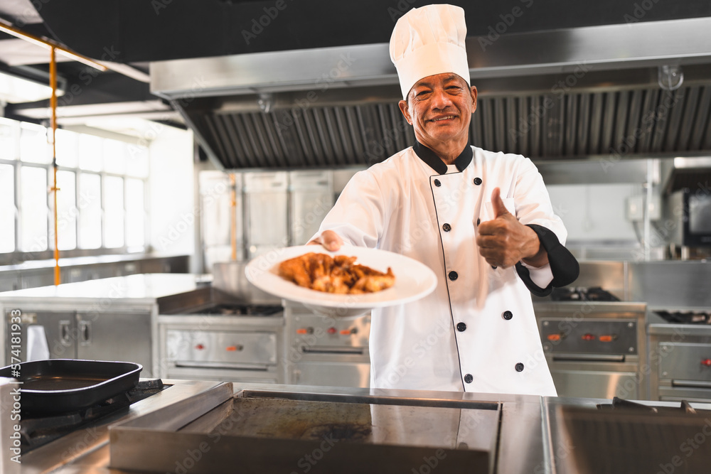 Asia senior chef holding omelet with thump up at big kitchen Asia senior chef holding omelet with thump up at big kitchen