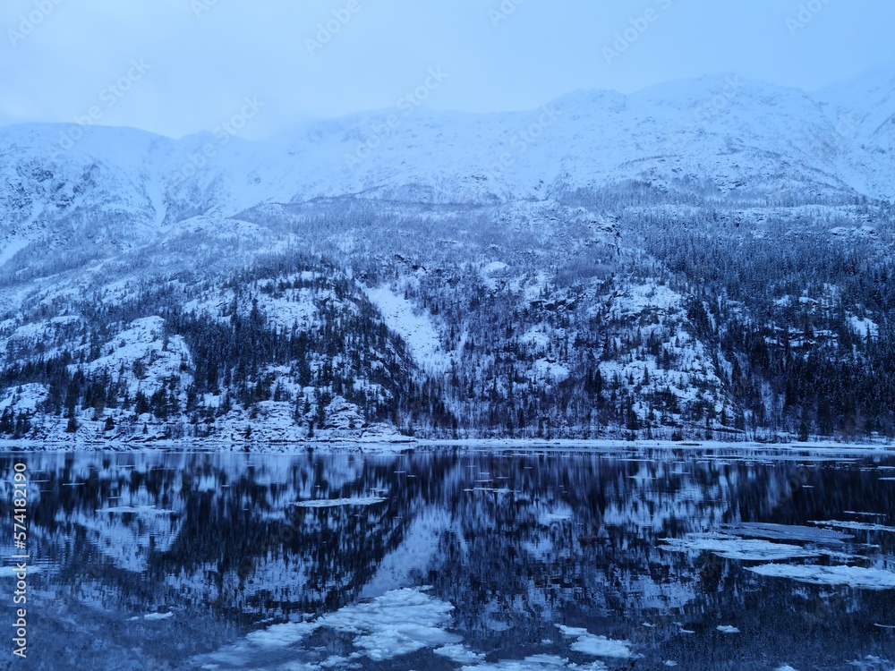 floating ice flakes on water with mountain reflection on surface