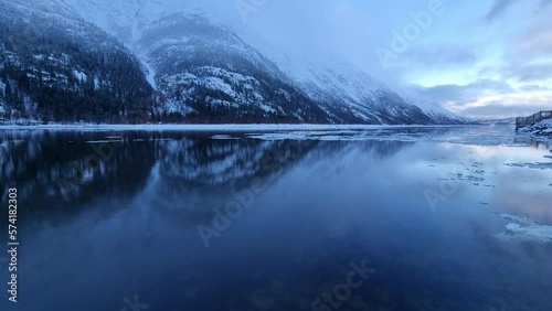floating ice flakes on water with mountain reflection on surface and moving clouds, timelapse video
