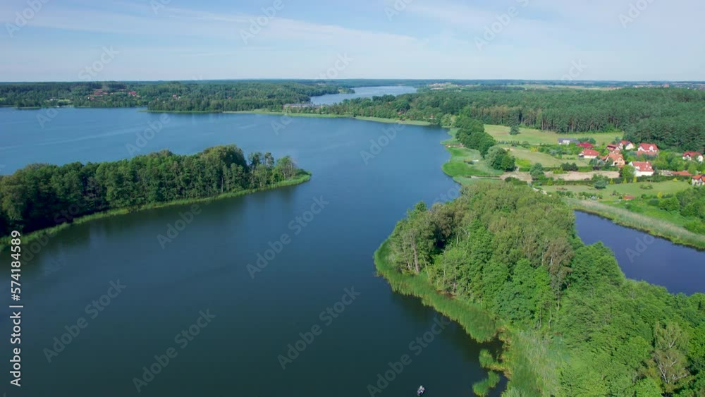 Majestic Aerial View of Calm Lake With Islands in Poland. Impressive Lake Houses. Village Houses on Shore of Paradise Lake. Peaceful Reflected on Water. Cottages Between Green Trees, Forest and Hills. Majestic Aerial View of Calm Lake With Islands in Poland. Impressive Lake Houses. Village Houses on Shore of Paradise Lake. Peaceful Reflected on Water. Cottages Between Green Trees, Forest and Hills.