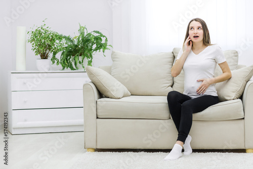 Photo of cute pregnant woman sitting on sofa.