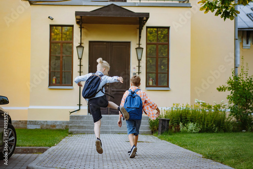 children running to school with backpacks on sunny day. Begining of academic year. Boys by school doorstep © Yulia Raneva