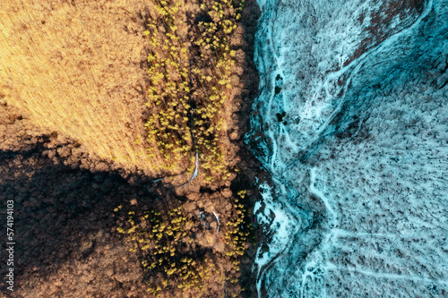 a field, part covered with snow, part not. picture from above photo