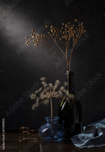 Modern still life with dry branches in glass vases on a dark background