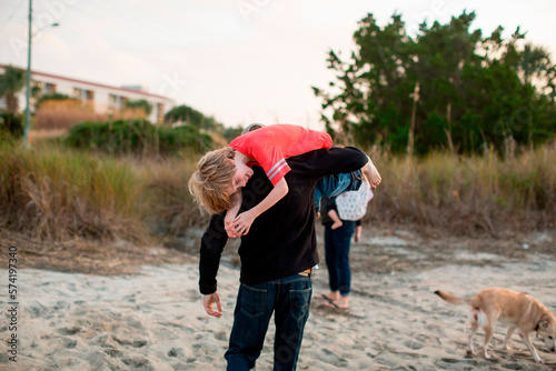A man carries his son over his shoulder in a marsh at Wrightsville Beach, NC.