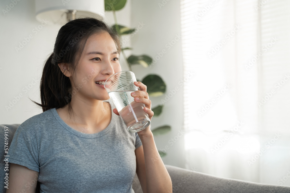 Healthy beautiful Asian woman is drinking and sip glass of fresh water everyday routine for body hydration by holding transparent glass in her hand, feel thirsty at home in the morning Healthy beautiful Asian woman is drinking and sip glass of fresh water everyday routine for body hydration by holding transparent glass in her hand, feel thirsty at home in the morning