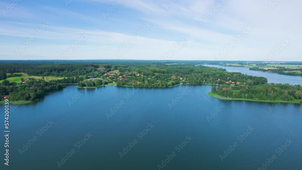Majestic Aerial View of Calm Lake With Islands in Poland. Impressive Lake Houses. Village Houses on Shore of Paradise Lake. Peaceful Reflected on Water. Cottages Between Green Trees, Forest and Hills. Majestic Aerial View of Calm Lake With Islands in Poland. Impressive Lake Houses. Village Houses on Shore of Paradise Lake. Peaceful Reflected on Water. Cottages Between Green Trees, Forest and Hills.