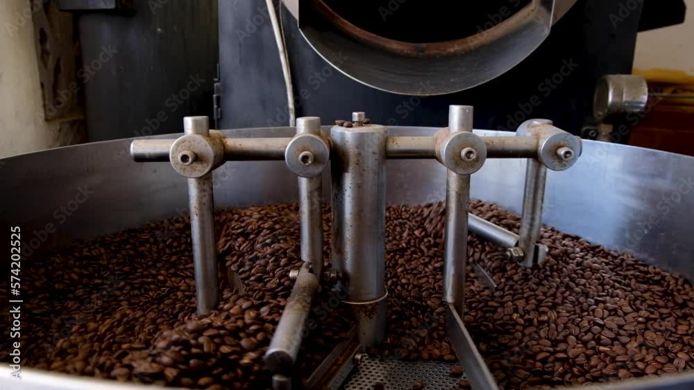Close up of Arabica coffee beans freshly roasted in professional industrial coffee roasting machine, golden dark brown coffee beans Close up of Arabica coffee beans freshly roasted in professional industrial coffee roasting machine, golden dark brown coffee beans