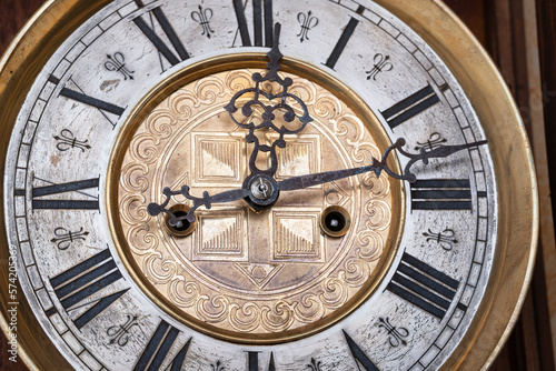 Old wooden clock with a pendulum hanging on the wall