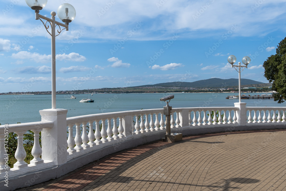 Gelendzhik bay. Embankment of resort town on blurred background of sea and mountains. Selective focus. Footpath along embankment is paved with paving slabs. Atmosphere of serene rest and relaxation.