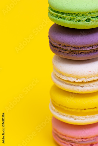 Traditional french multicolored macaroons falling on yellow  background