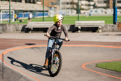helmeted child learns on a bicycle track