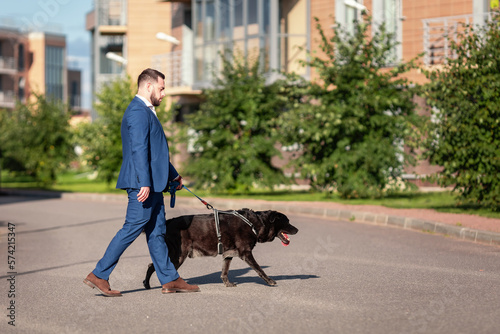 A businessman walking his dog in the urban exterior. Young handsome man with a dog on a leash.