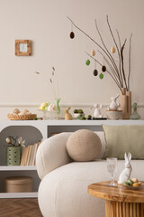 Spring composition of easter living room interior with mock up poster frame,  modern sideboard, coffee table easter eggs, round pillow, easter bunny and personal accessories. Home decor. Template.