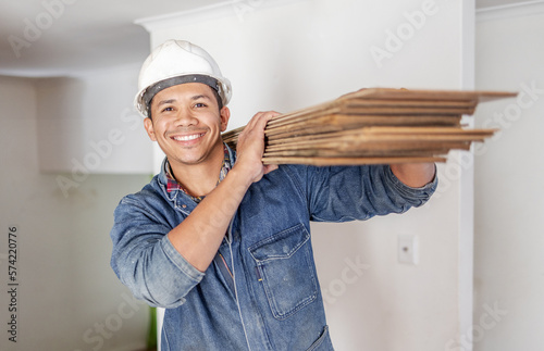 Construction worker, home renovation and portrait of man holding wood for maintenance. Working, smile and house development project employee and builder or handyman for architecture or industrial job