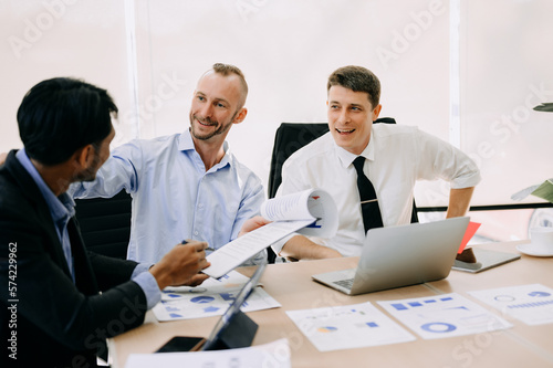Office colleagues have a casual discussion. During a meeting in conference room, a group of business teem sit in the conference room new startup project..