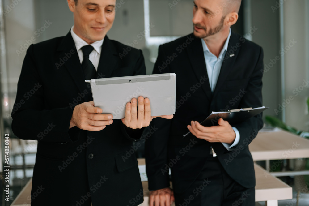 Kind leader executive manager share and discuss business solutions plan ideas on tablet with male marketing manager in modern office..