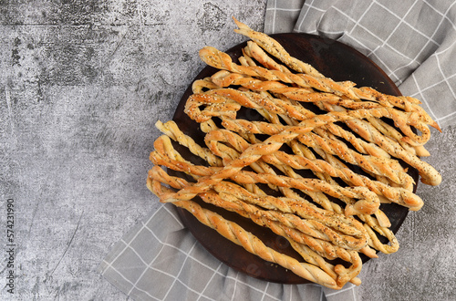 Homemade Grissini Italian Breadsticks on a round plate on a dark grey background. Top view, flat lay