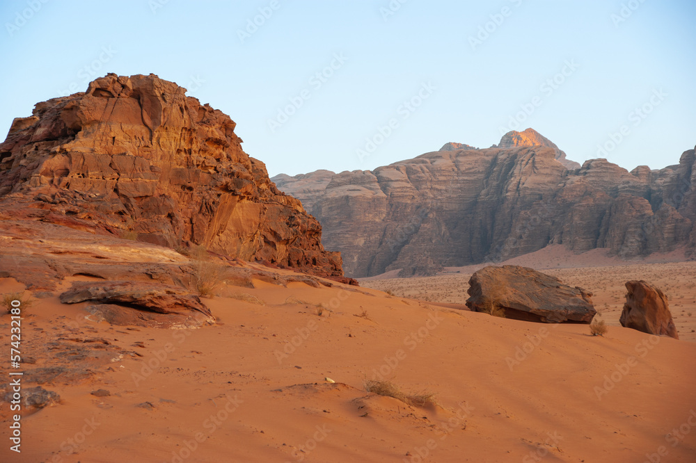 Fototapeta premium Bizarre shapes of rocks in deserted desert. Jordan. Desert of Wadi Rum. Landscape is similar to Martian landscapes. Sand is of beautiful pink color in rays of setting sun. Nature concept for design