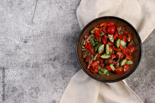 Healthy Cucumber Salad with Tomatoes, Pink Onions ia a bowl on a dark background. Top view, flat lay