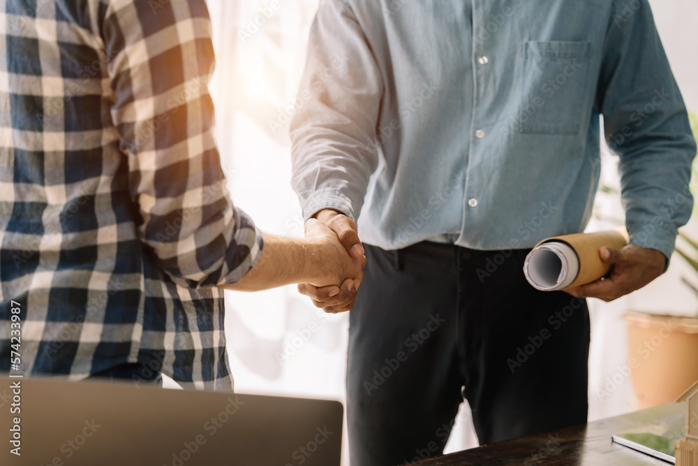 Construction workers, engineers shake hands while working for teamwork and cooperation after completing an agreement in an office facility, successful cooperation concept.