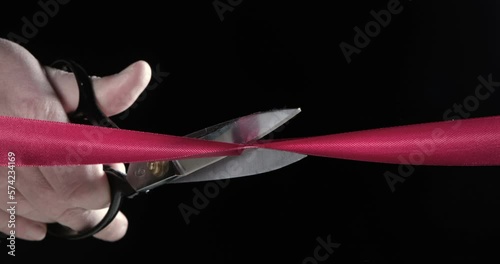 Red tape on a black background, scissors solemnly cut
