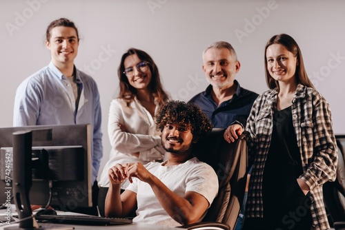 Smiling startup team in coworking center. Indoor shot of coworkers in casual outfit posing in office