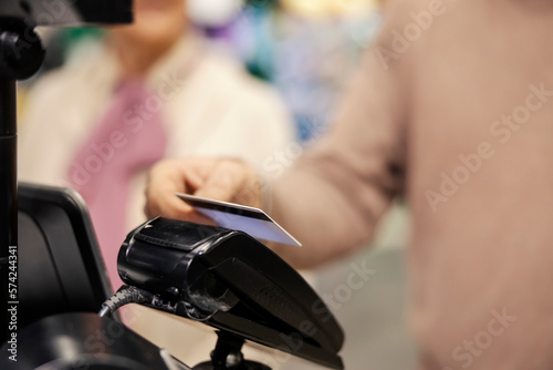 Close up of a senior man paying with credit card on self-service cash register in supermarket.