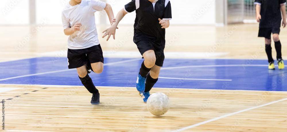 School boys on indoor football tournament game. Football futsal players, ball, futsal floor. Indoor soccer sports hall. Kids compete in indoor soccer duel