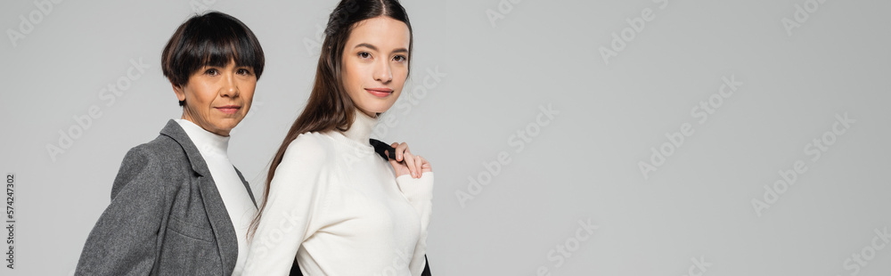 young woman in black turtleneck looking at camera near asian mother isolated on grey, banner young woman in black turtleneck looking at camera near asian mother isolated on grey, banner