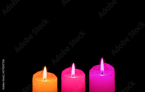 Burning Three of Different Vibrant Colors Candles on Black Backdrop with Copy Space