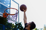 handsome basketball player shooting a ball through the hoop while playing on basketball court outdoors
