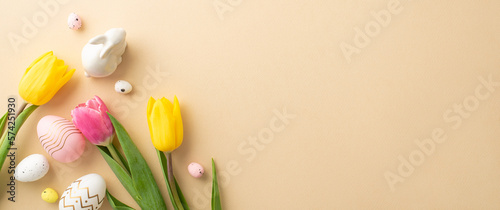 Easter concept. Top view photo of colorful easter eggs ceramic bunny and tulips on isolated pastel beige background with copyspace