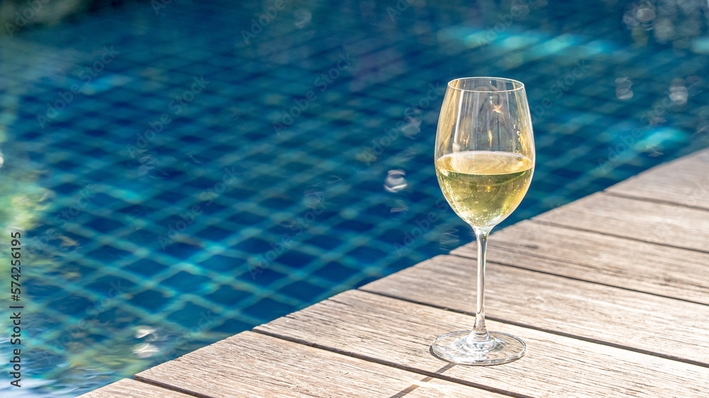 white wine glass on wooden floor near pool. Golden champagne Wine for cozy relax outdoor in holiday. travel drink in summer vacation outside resort house. white wine glass on wooden floor near pool. Golden champagne Wine for cozy relax outdoor in holiday. travel drink in summer vacation outside resort house.