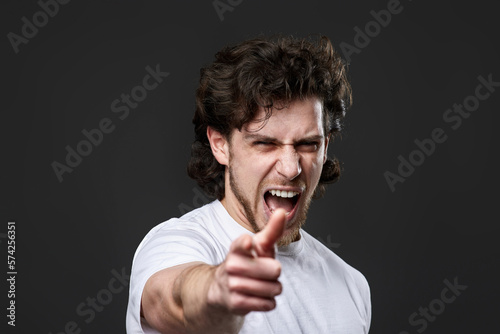 caucasian man pointing finger at you and the camera on dark gray background