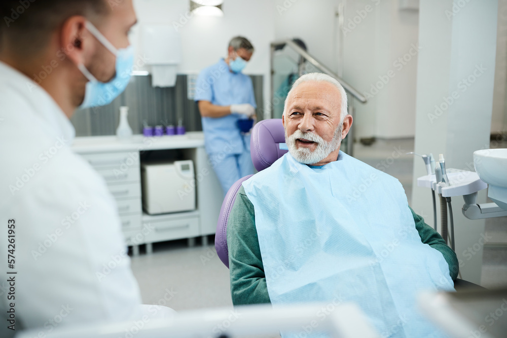 Happy senior man talks to his dentist during teeth check-up at dental clinic. Happy senior man talks to his dentist during teeth check-up at dental clinic.