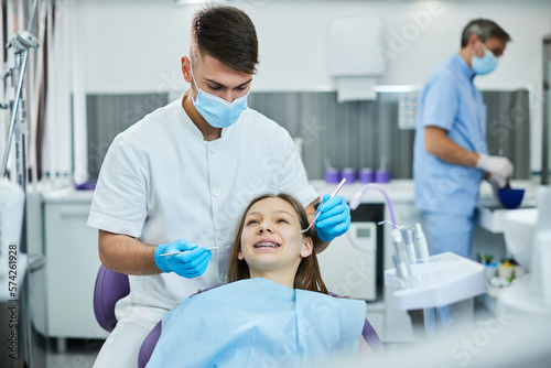 Smiling teenage girl getting dental braces at dentist's office.