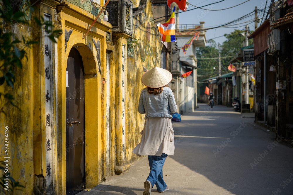 Unrecognizable woman in traditional cone hat walking along street Unrecognizable woman in traditional cone hat walking along street
