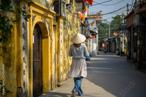 Unrecognizable woman in traditional cone hat walking along street © Gabriel Trujillo