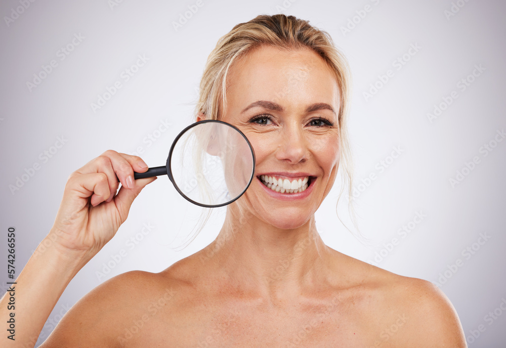 Portrait, beauty and magnifying glass with a mature woman in studio on a gray background to examine her skin. Face, wrinkle and antiaging with an attractive female confident in her natural skincare Portrait, beauty and magnifying glass with a mature woman in studio on a gray background to examine her skin. Face, wrinkle and antiaging with an attractive female confident in her natural skincare