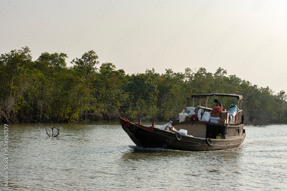 Fototapeta premium 11th February, 2023, Sundarban, West Bengal, India: Few ferry boats carrying daily needs items on the river at Sundarban Tiger reserve, India.